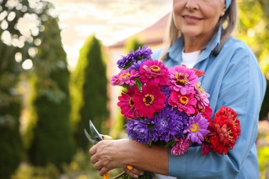 Photo of Senior woman with bouquet of flowers and pruner in garden, closeup. Space for text