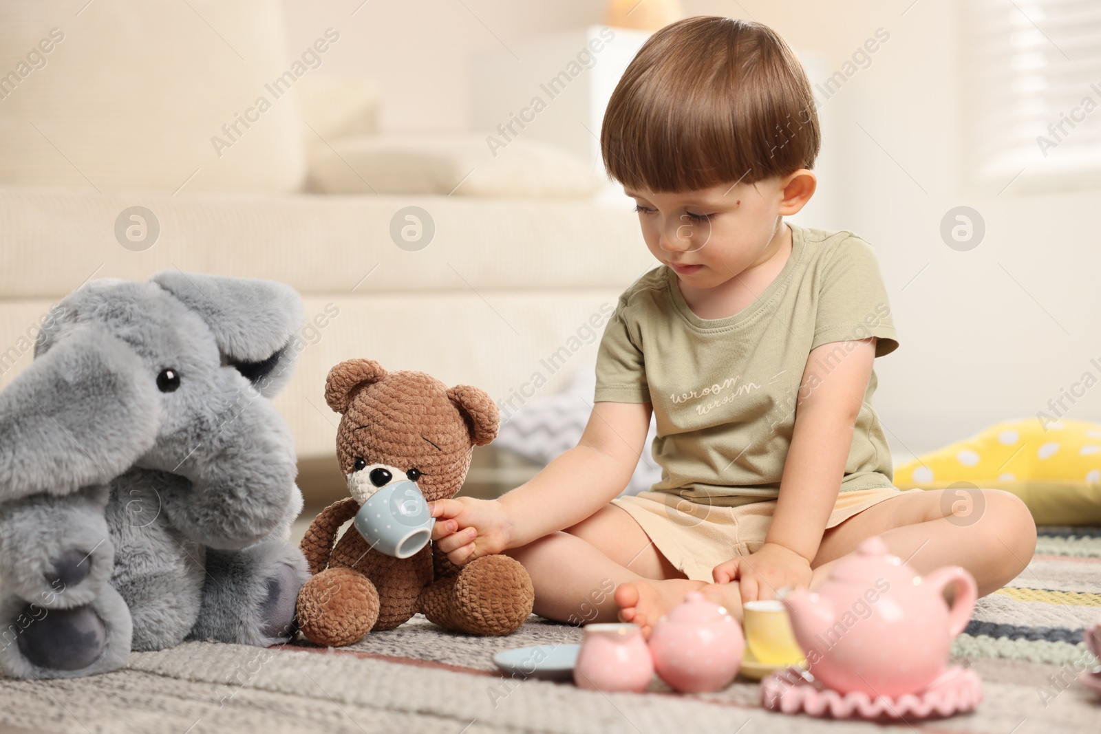 Photo of Cute little boy playing tea party with his toys indoors