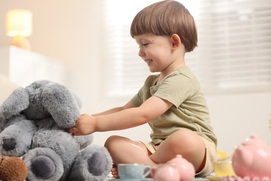 Photo of Cute little boy playing tea party with his toy elephant indoors