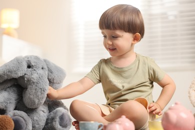 Photo of Cute little boy playing tea party with his toy elephant indoors