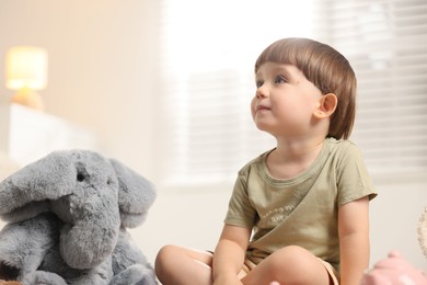 Photo of Cute little boy playing tea party with his toy elephant indoors. Space for text