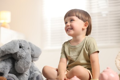 Photo of Cute little boy playing tea party with his toy elephant indoors. Space for text