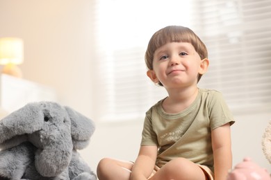 Photo of Cute little boy playing tea party with his toy elephant indoors. Space for text
