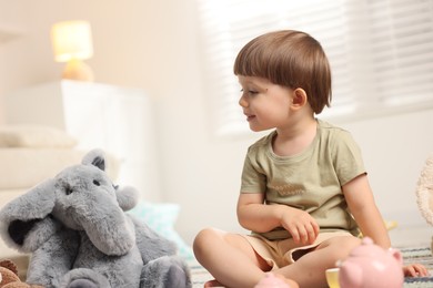Photo of Cute little boy playing tea party with his toy elephant indoors. Space for text