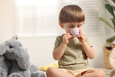 Photo of Cute little boy playing tea party with his toy elephant indoors. Space for text
