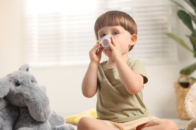 Photo of Cute little boy playing tea party with his toy elephant indoors. Space for text