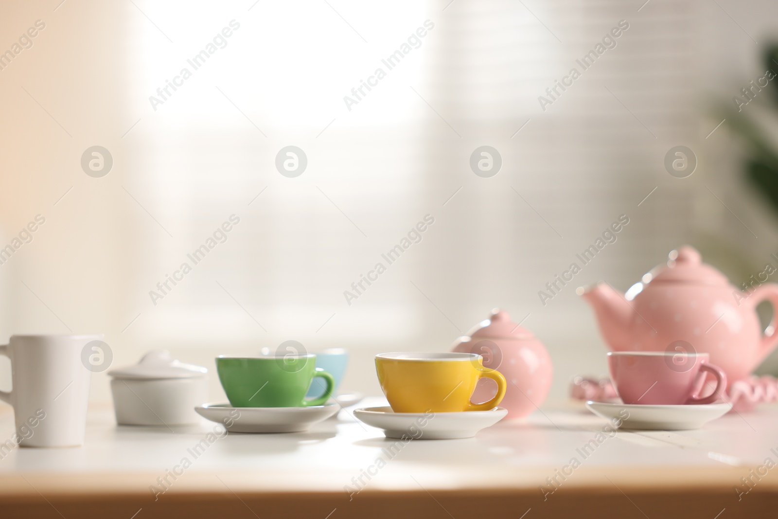 Photo of Tea set on white table indoors, closeup with space for text. Child's toy