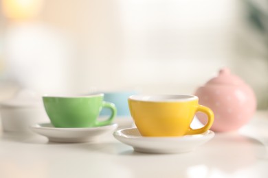 Photo of Tea set on white table indoors, closeup with space for text. Child's toy