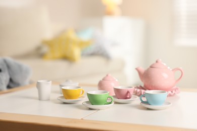 Photo of Tea set on white table indoors, closeup with space for text. Child's toy