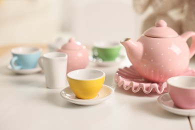 Photo of Tea set on white table indoors, closeup. Child's toy