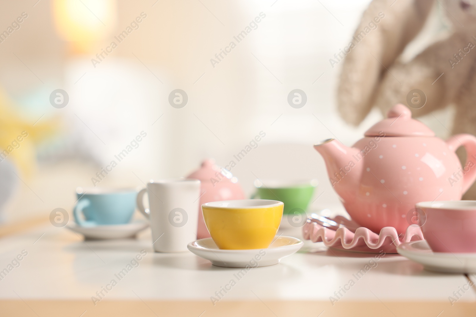 Photo of Tea set on white table indoors, closeup with space for text. Child's toy