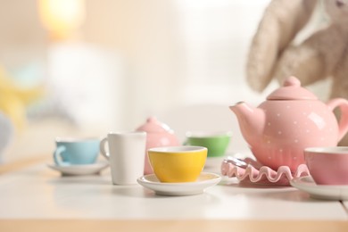 Photo of Tea set on white table indoors, closeup with space for text. Child's toy