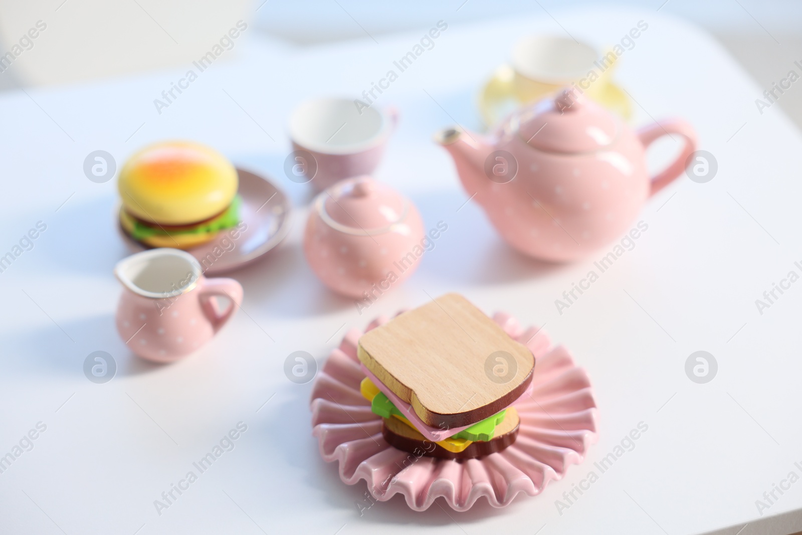Photo of Tea set on white table indoors, closeup. Child's toy