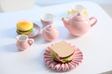 Photo of Tea set on white table indoors, closeup. Child's toy