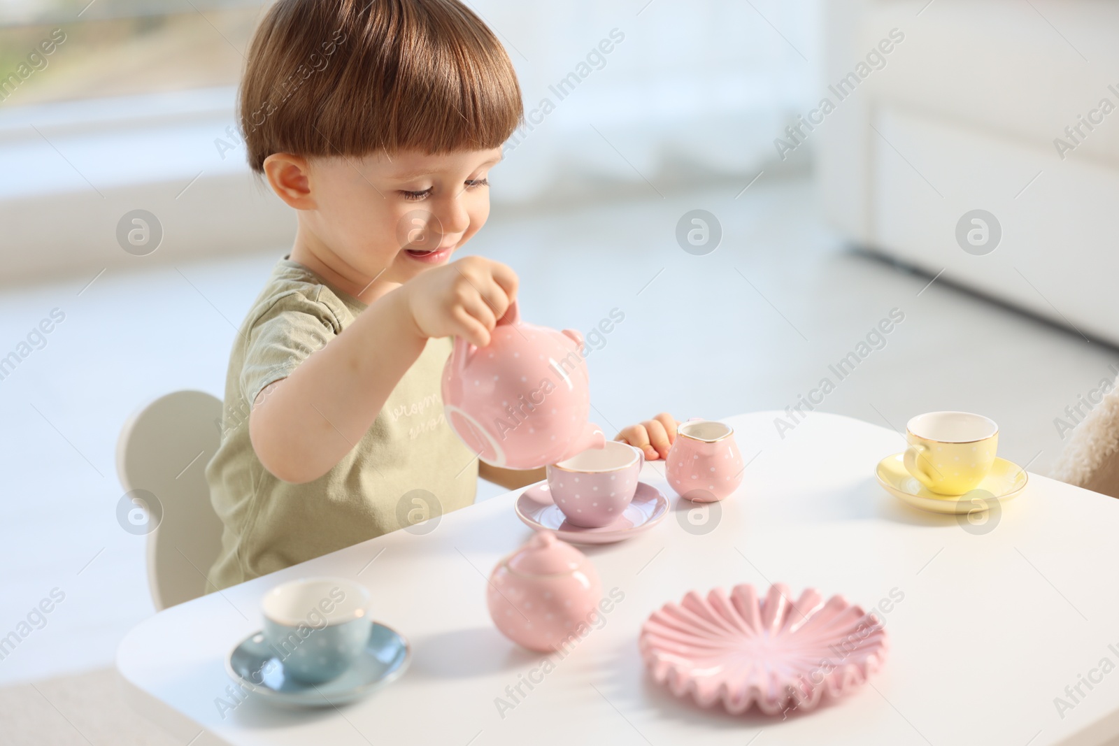 Photo of Cute little boy playing with toy tea set at table indoors. Space for text
