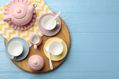 Photo of Beautiful ceramic tea set for children and napkin on light blue wooden table, top view. Space for text