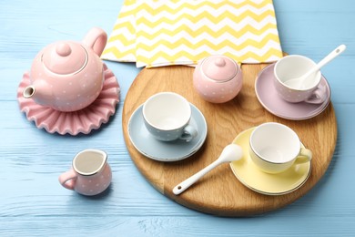 Photo of Beautiful ceramic tea set for children and napkin on light blue wooden table