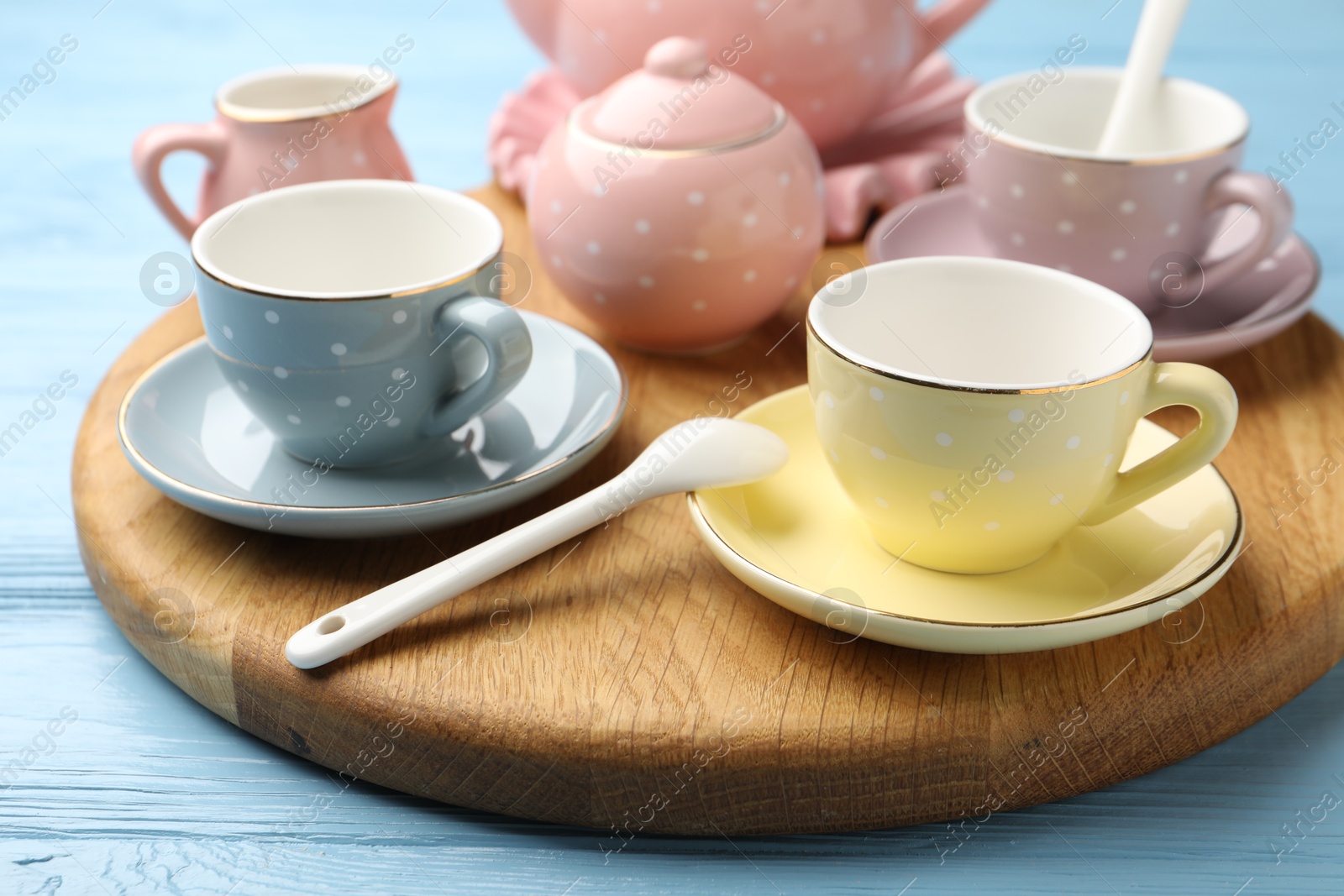 Photo of Beautiful ceramic tea set for children on light blue wooden table, closeup
