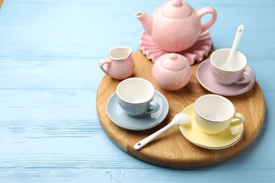 Photo of Beautiful ceramic tea set for children on light blue wooden table, closeup. Space for text