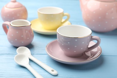 Photo of Beautiful ceramic tea set for children on light blue wooden table, closeup