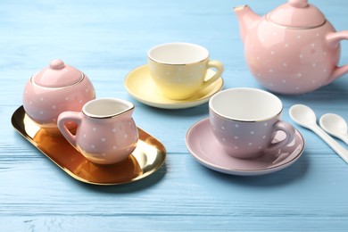 Photo of Beautiful ceramic tea set for children on light blue wooden table, closeup
