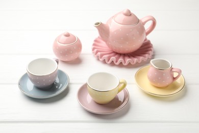 Photo of Beautiful ceramic tea set for children on white wooden table, closeup