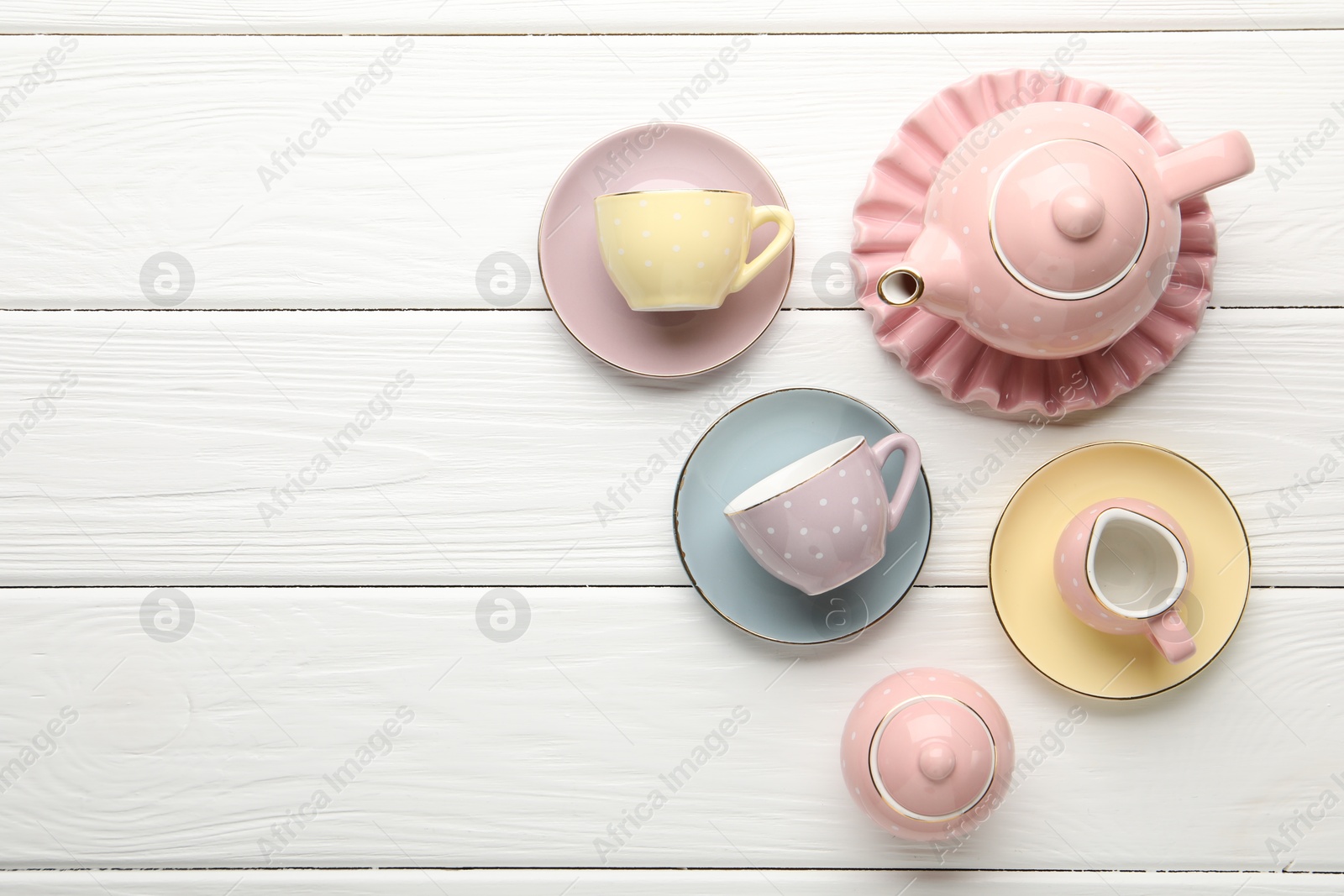 Beautiful ceramic tea set for children on white wooden table, flat lay. Space for text Photo of Beautiful ceramic tea set for children on white wooden table, flat lay. Space for text