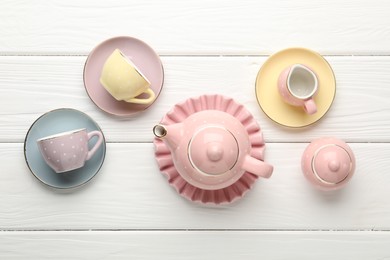 Photo of Beautiful ceramic tea set for children on white wooden table, flat lay