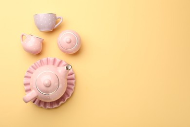 Photo of Beautiful ceramic tea set for children on yellow background, flat lay. Space for text