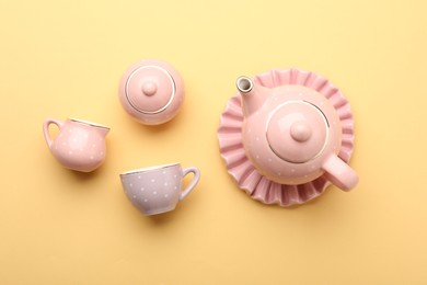 Photo of Beautiful ceramic tea set for children on yellow background, flat lay