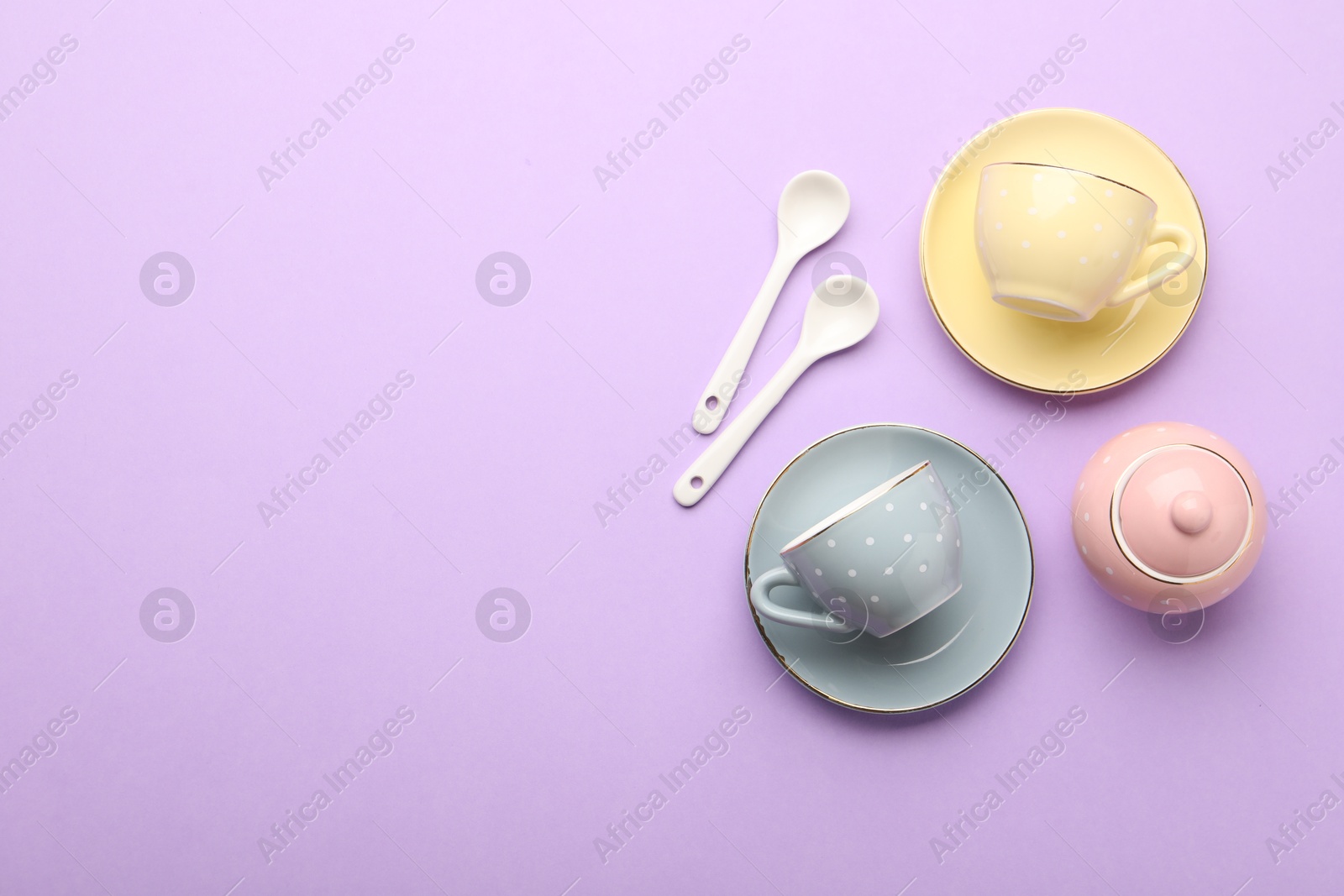 Photo of Beautiful ceramic tea set for children on violet background, flat lay. Space for text