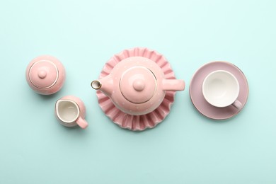 Photo of Beautiful ceramic tea set for children on turquoise background, flat lay