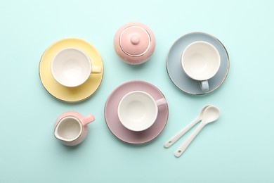 Photo of Beautiful ceramic tea set for children on turquoise background, flat lay