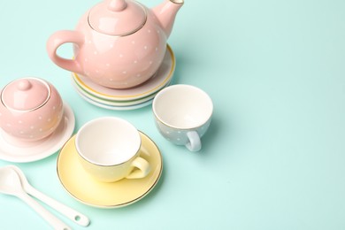 Photo of Beautiful ceramic tea set for children on turquoise background. Space for text