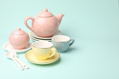 Photo of Beautiful ceramic tea set for children on turquoise background. Space for text