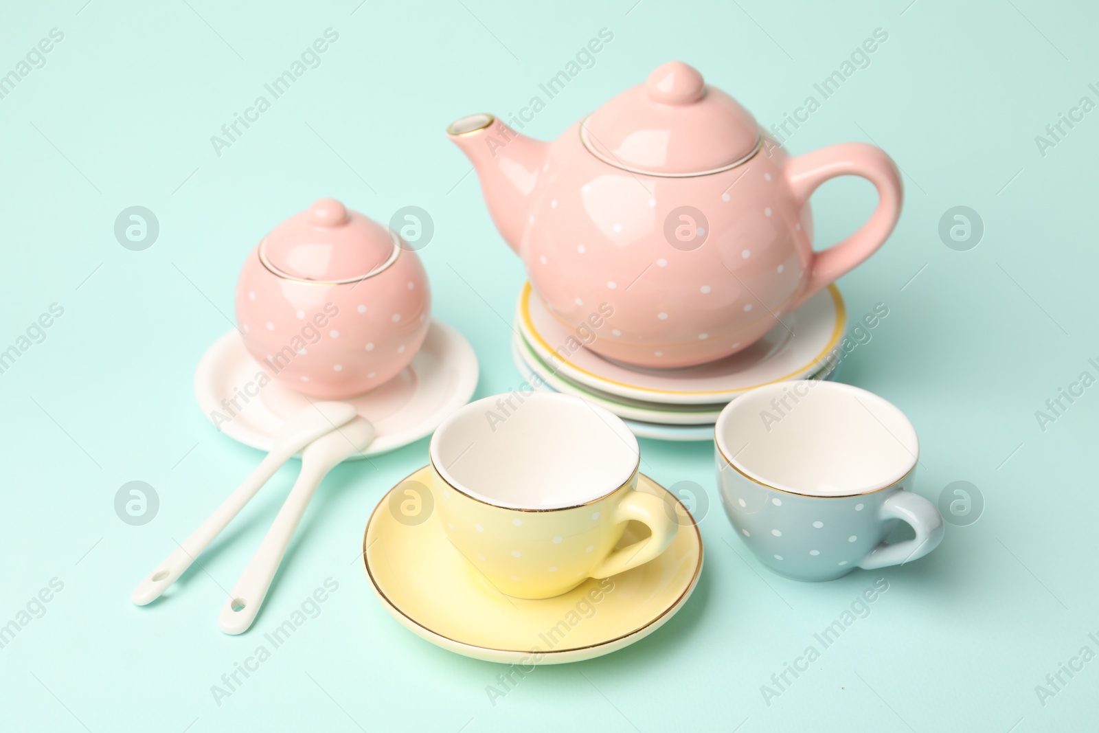 Photo of Beautiful ceramic tea set for children on turquoise background, closeup