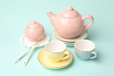 Photo of Beautiful ceramic tea set for children on turquoise background, closeup