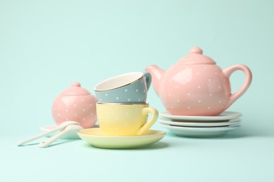 Photo of Beautiful ceramic tea set for children on turquoise background, closeup