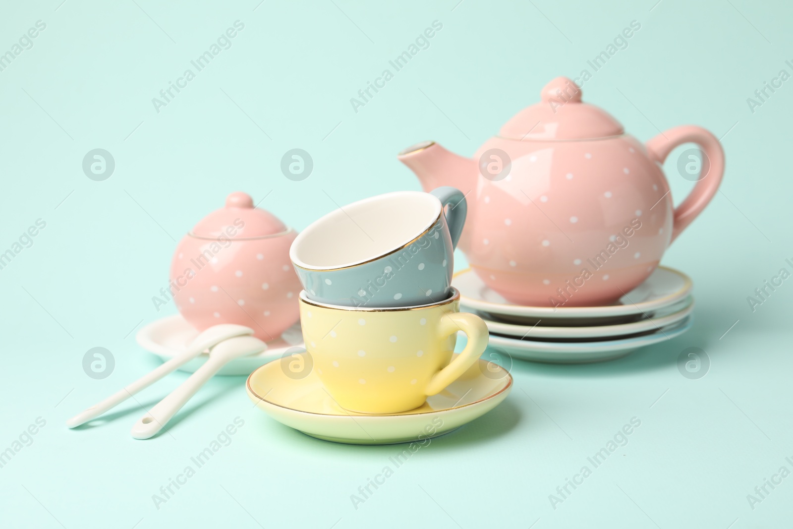 Photo of Beautiful ceramic tea set for children on turquoise background, closeup