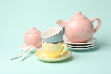 Photo of Beautiful ceramic tea set for children on turquoise background, closeup