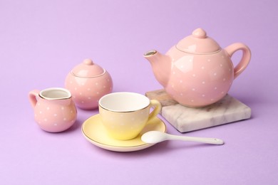 Photo of Beautiful ceramic tea set for children on violet background, closeup