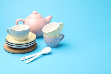 Photo of Beautiful ceramic tea set for children on light blue background. Space for text