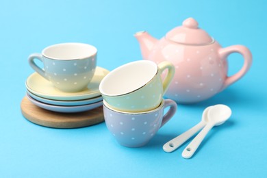 Photo of Beautiful ceramic tea set for children on light blue background, closeup