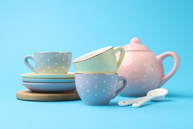 Photo of Beautiful ceramic tea set for children on light blue background, closeup