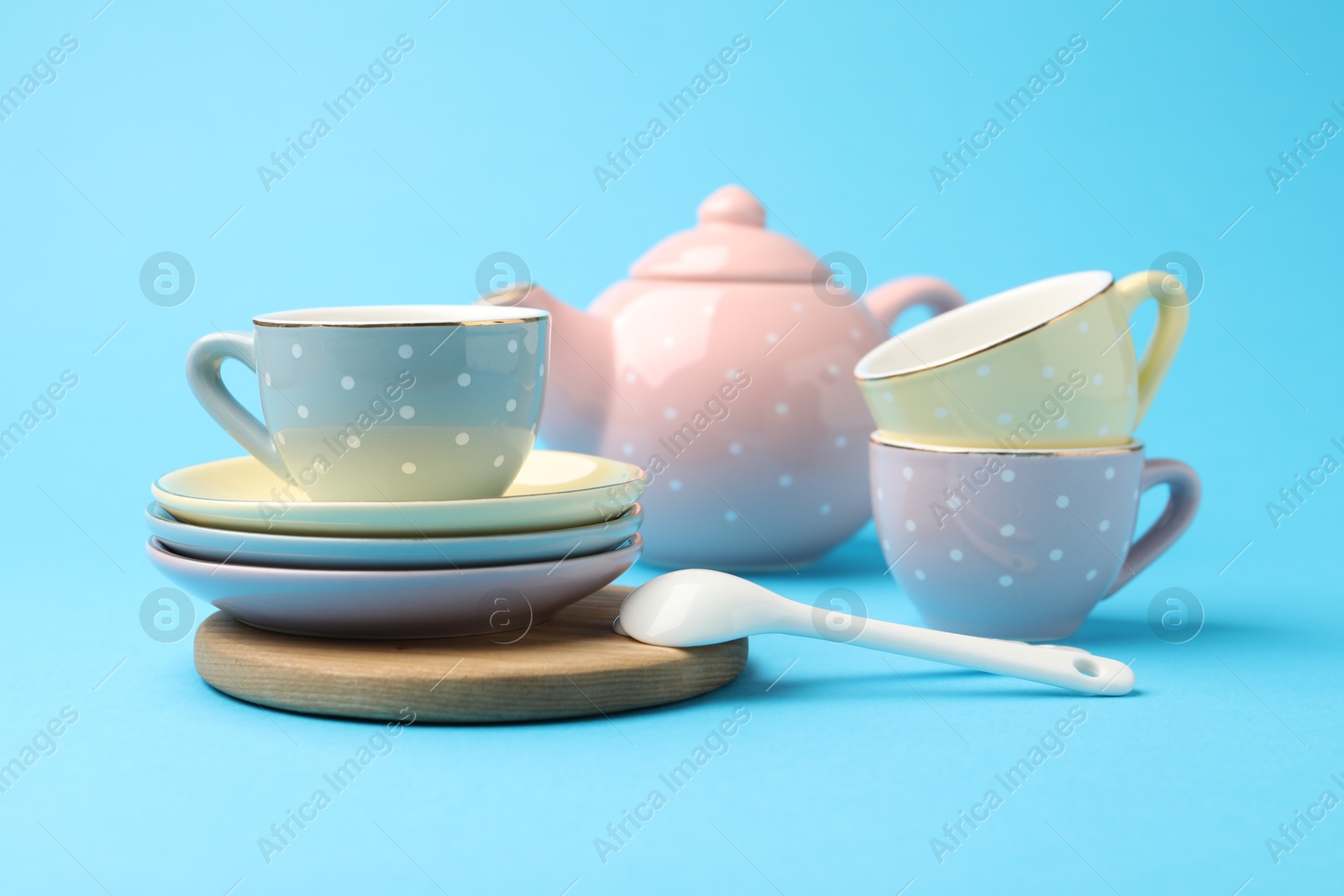 Photo of Beautiful ceramic tea set for children on light blue background, closeup