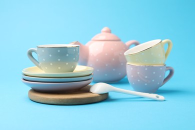 Photo of Beautiful ceramic tea set for children on light blue background, closeup
