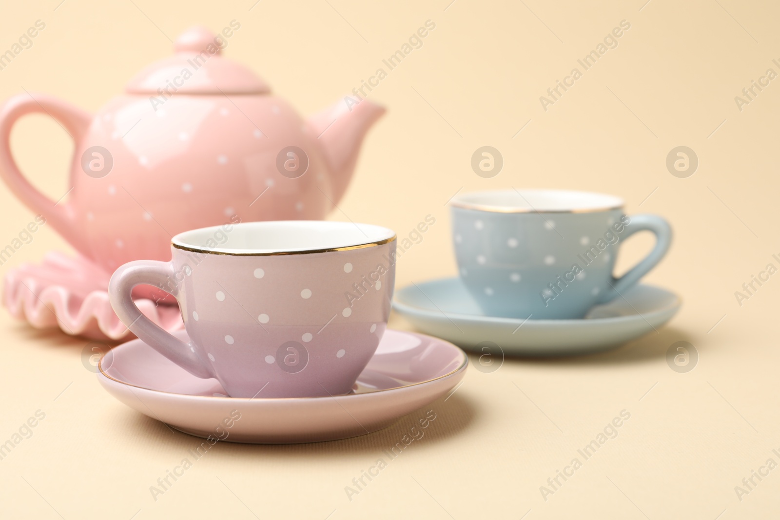 Photo of Beautiful ceramic tea set for children on beige background, closeup