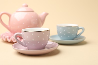 Photo of Beautiful ceramic tea set for children on beige background, closeup