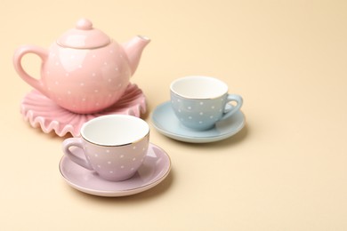 Photo of Beautiful ceramic tea set for children on beige background, closeup. Space for text