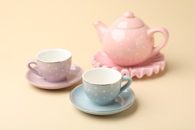 Photo of Beautiful ceramic tea set for children on beige background, closeup